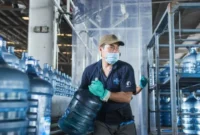 Seorang pekerja memindahkan galon guna ulang berisi air minum.(poto: padangkita.com).