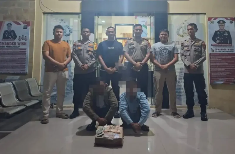 Personel Polsek Pasaman mengamankan dua tersangka pungli di Pantai Sasak, Kabupaten Pasaman Barat, dengan barang bukti kotak kardus minuman dan uang tunai.( poto: koranpadang.com)