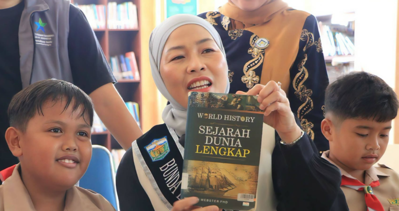Bunda Literasi Kota Sungai Penuh, Sri Kartini Alfin, S.Kep., Ns, saat berada di perpustakaan dan menujnjukkan buku.(poto: istimewa).