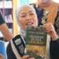 Bunda Literasi Kota Sungai Penuh, Sri Kartini Alfin, S.Kep., Ns, saat berada di perpustakaan dan menujnjukkan buku.(poto: istimewa).