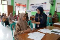 Petugas Agen Perlinsos mendampingi warga melakukan verifikasi wajah pendaftaran bansos 2027 di kantor kelurahan.(ilustrasi poto: AI).